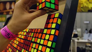 Hands arranging Rubik's cubes on a board.